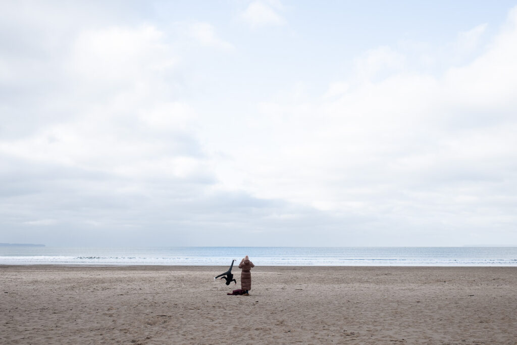 Parent with smaller child doing cartwheels on deserted beach