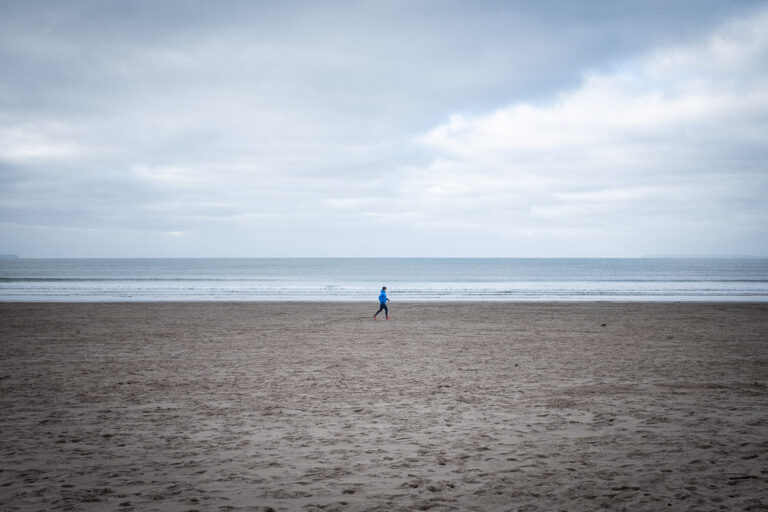 The Beach in Winter - Lone Jogger running along a deserted beach